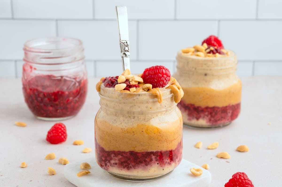 Jars of Peanut Butter and Jelly Overnight Oats Close-up of creamy Peanut Butter and Jelly Overnight Oats with fresh berries and crushed peanuts.
