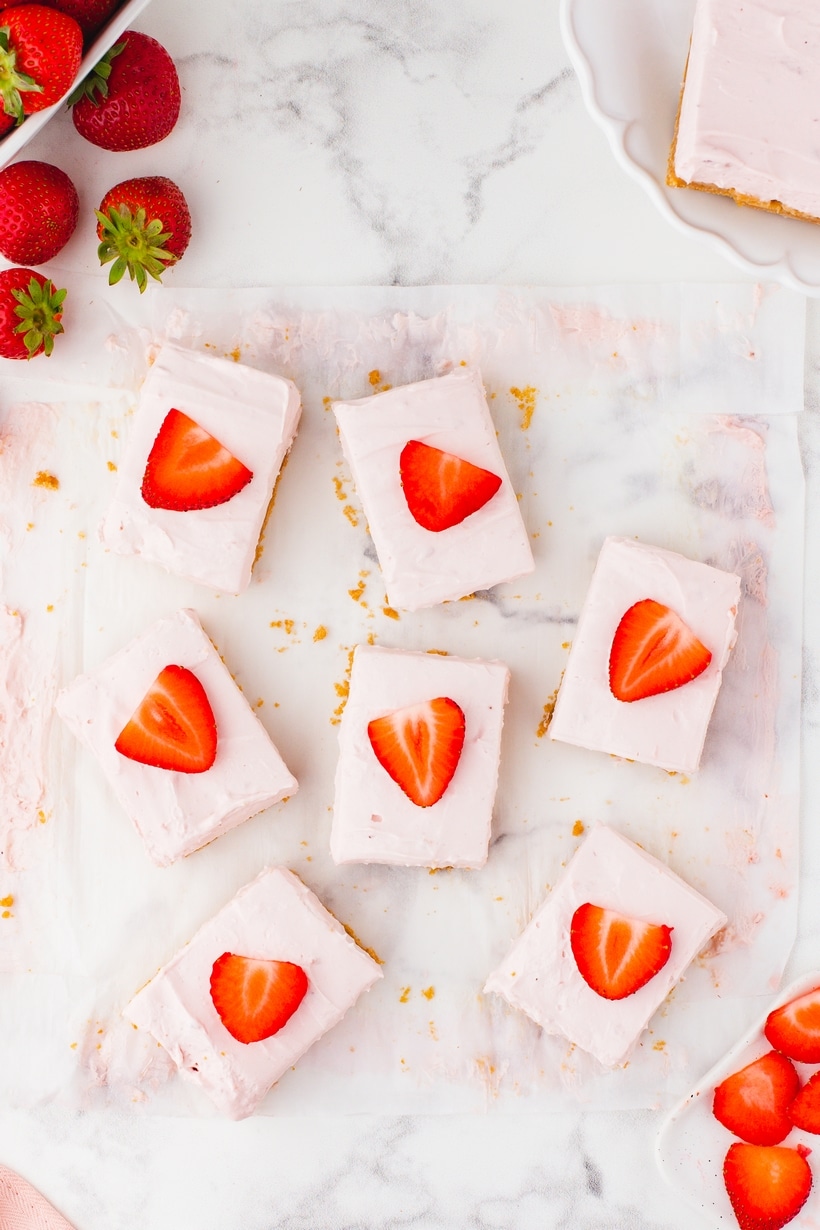 Overhead view of sliced strawberry cheesecake bars topped with fresh strawberry pieces