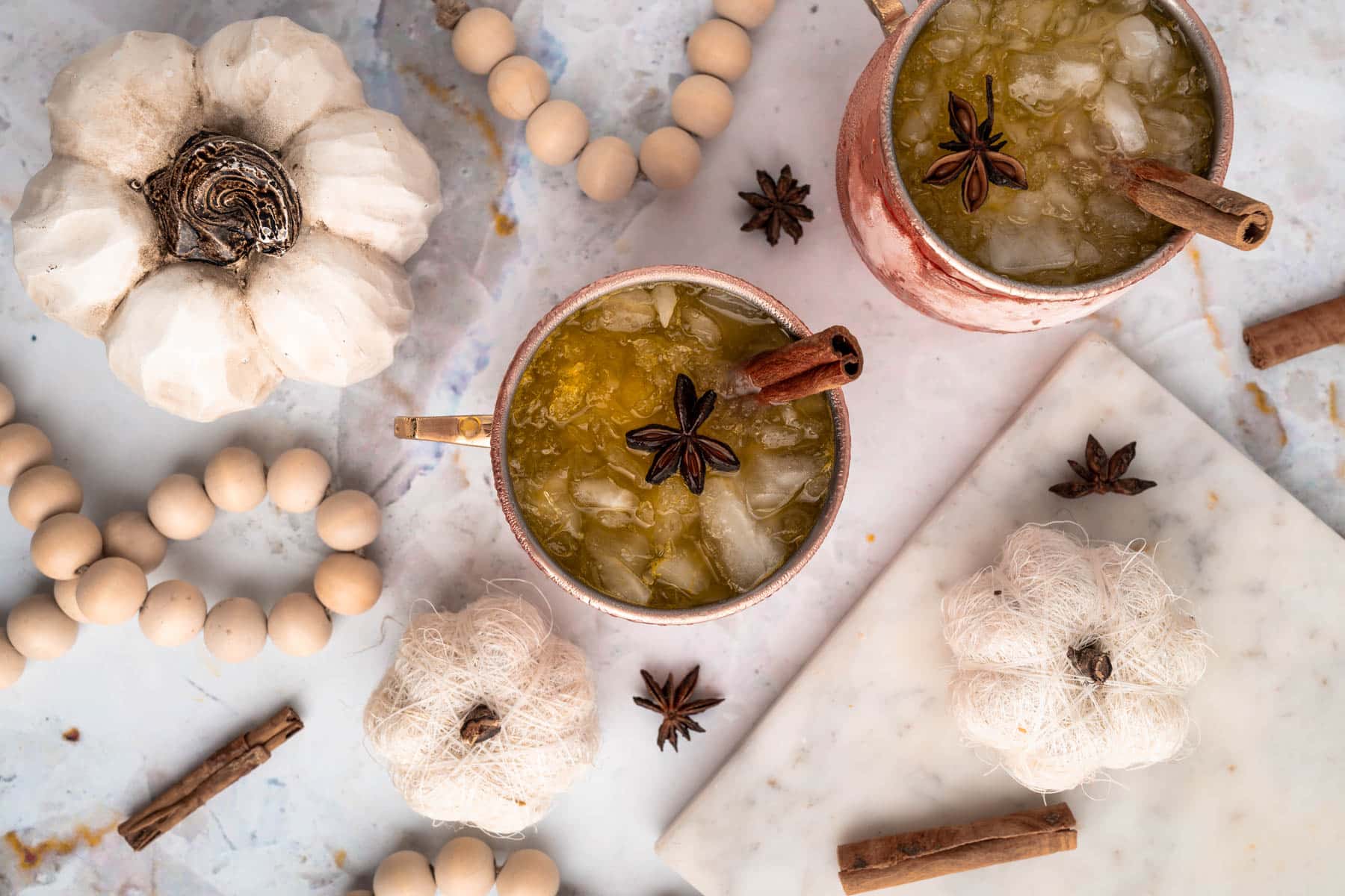 Garnished Pumpkin Spice Moscow Mules Overhead View Overhead shot of Pumpkin Spice Moscow Mules garnished with cinnamon sticks and star anise, surrounded by additional decor.