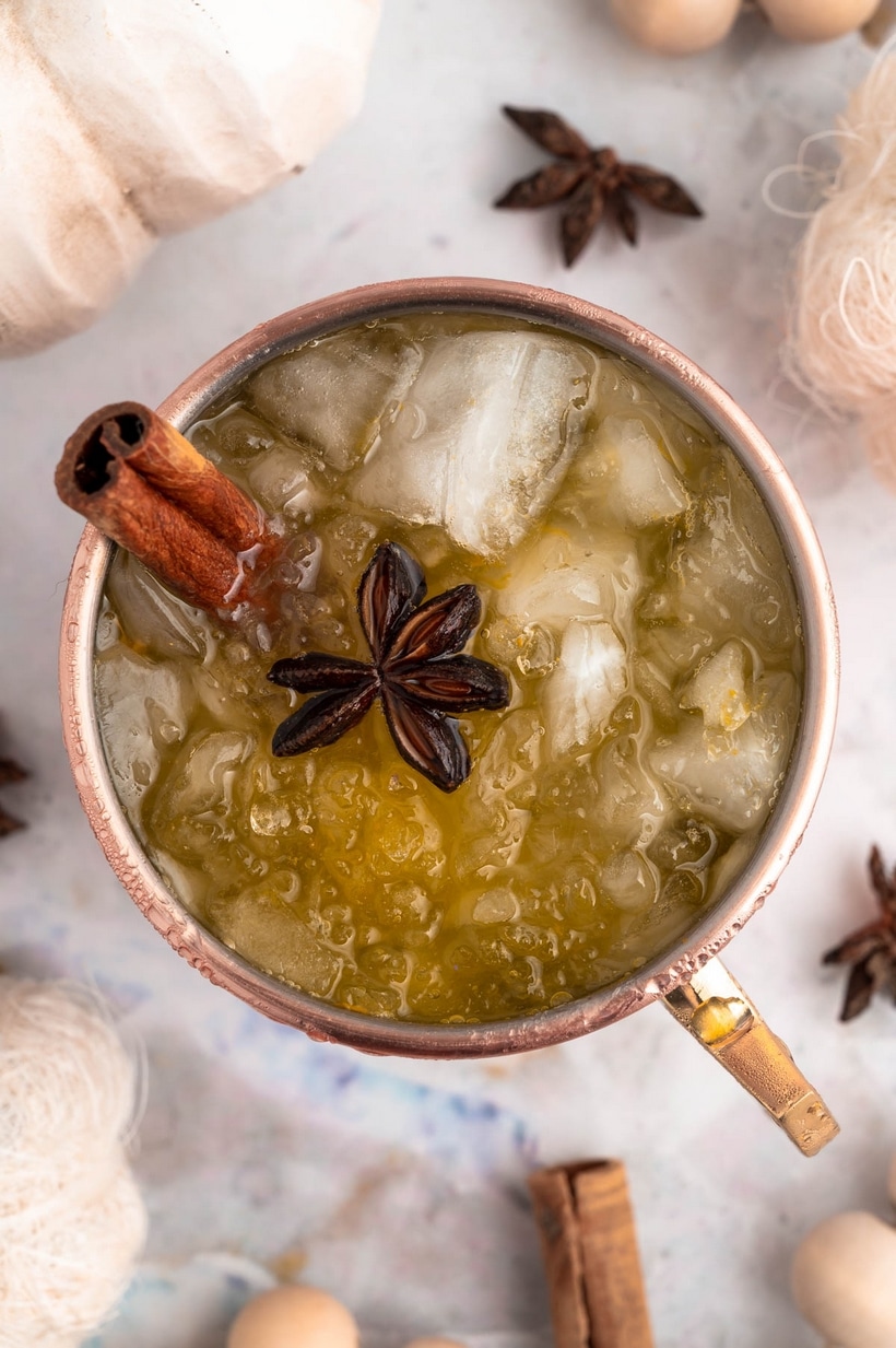 Close-up top view of Pumpkin Spice Moscow Mule Close-up of a Pumpkin Spice Moscow Mule in a copper mug, highlighting the garnish and icy top.