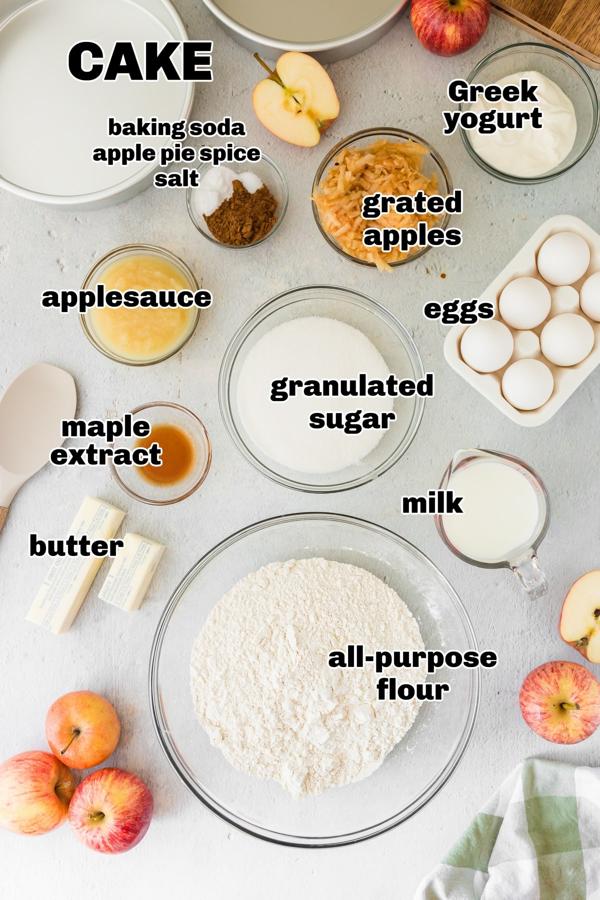 Caramel Apple Layer Cake Ingredients Assorted ingredients for caramel apple layer cake: flour, baking soda, apple pie spice, unsalted butter, granulated sugar, unsweetened applesauce, heavy cream, whole milk, maple extract, apples, Greek yogurt, brown sugar, confectioners' sugar, apple slices, and walnuts.