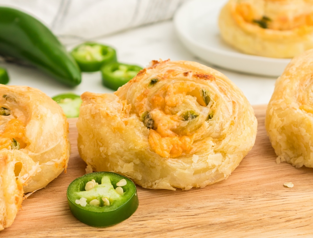 Jalapeno Popper Pinwheels on a cutting board. A close-up of Jalapeño Popper Pinwheels with a crispy golden exterior and gooey cheese filling peeking out.