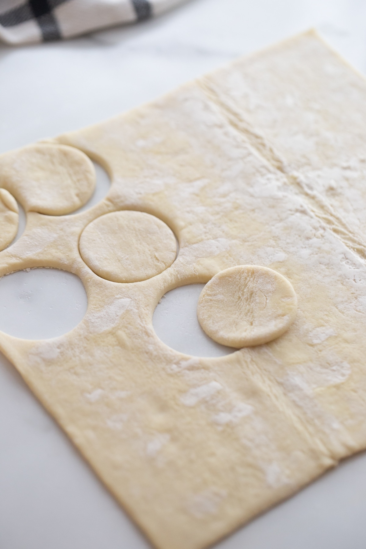 Cutting Rounds from Puff Pastry for Crab and Chive Puffs Puff pastry sheet with several rounds cut out using a cookie cutter.