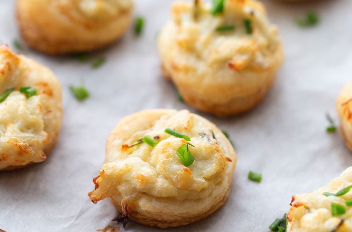 Close-Up of a Crab and Chive Puff Close-up view of a flaky, golden crab and chive puff showing the creamy filling.