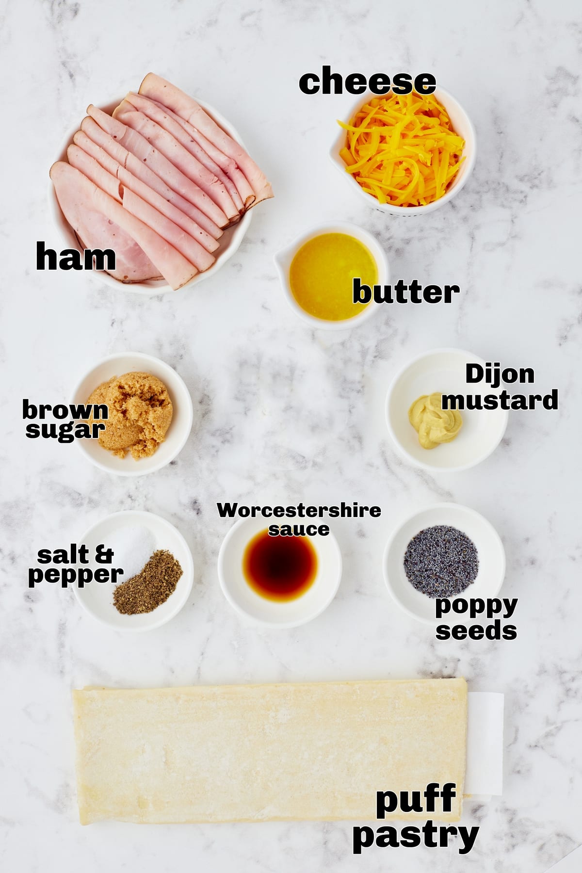 Ham and Cheese Pinwheels ingredients Ingredients laid out on a countertop: puff pastry, deli ham, shredded cheese, and seasoning.