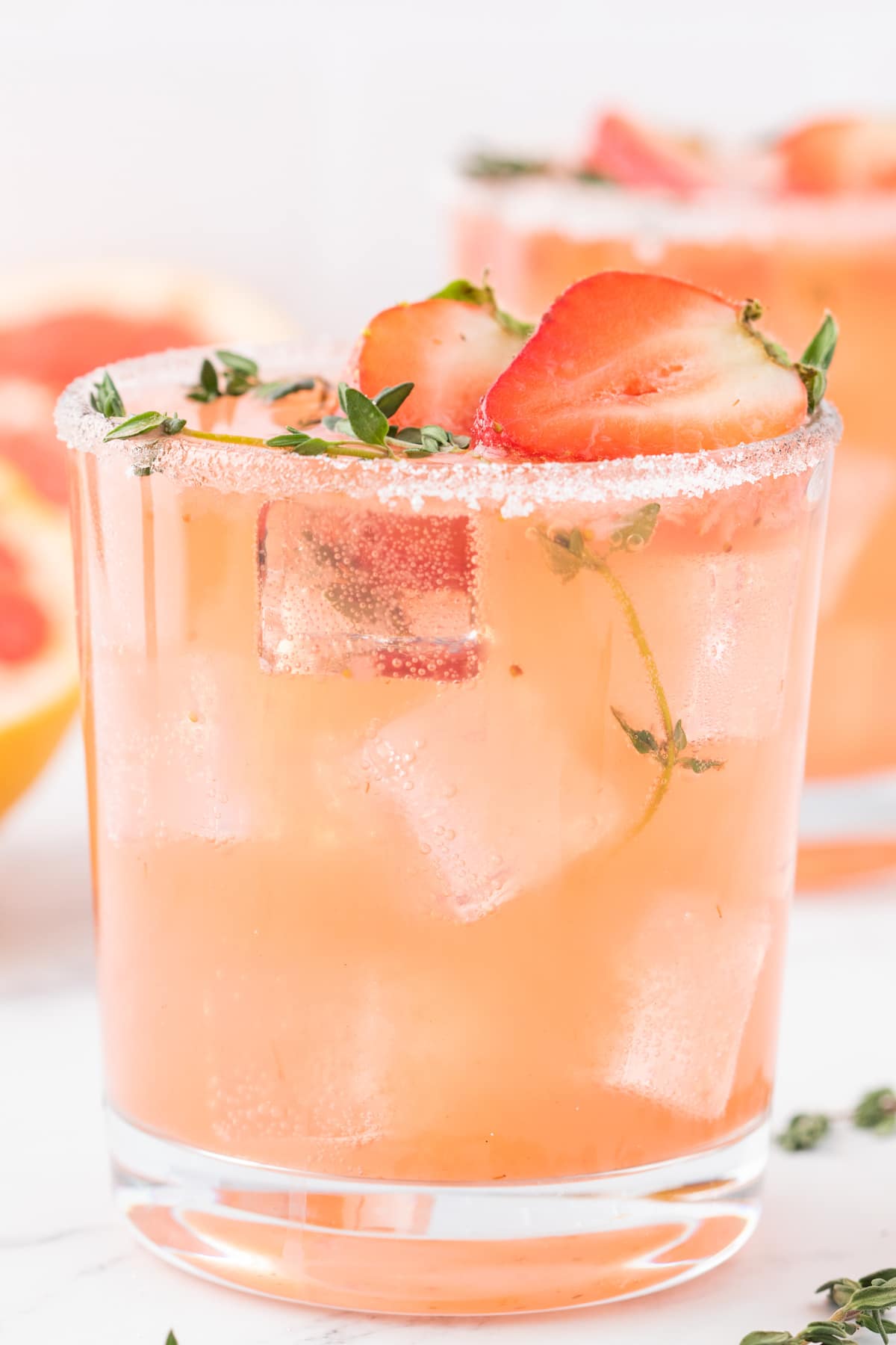 a single Strawberry Grapefruit Paloma Close-up of one paloma, highlighting the ice, fresh fruit garnish, and sugar-rimmed edge.