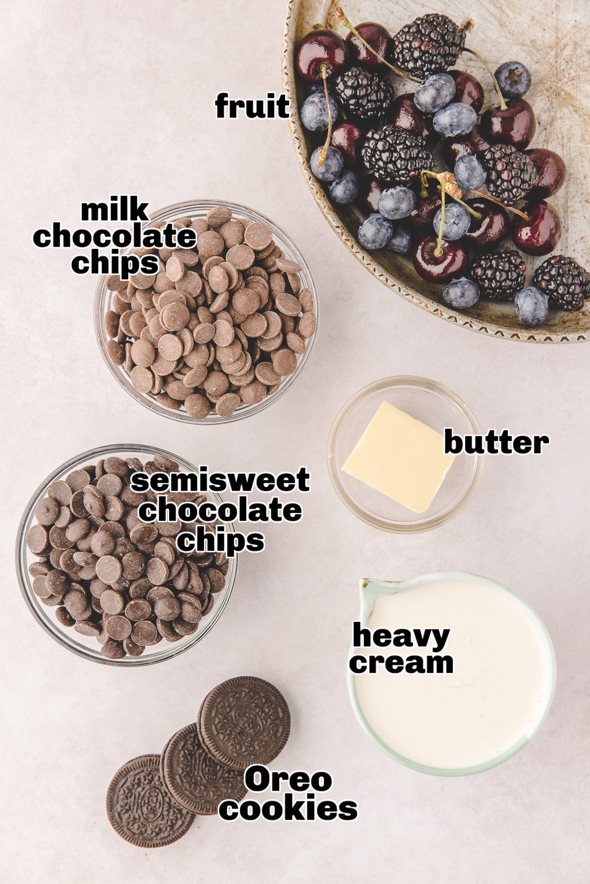 All five ingredients for the mini chocolate ganache tarts laid out on a countertop, including Oreos, butter, chocolate chips, and cream. 