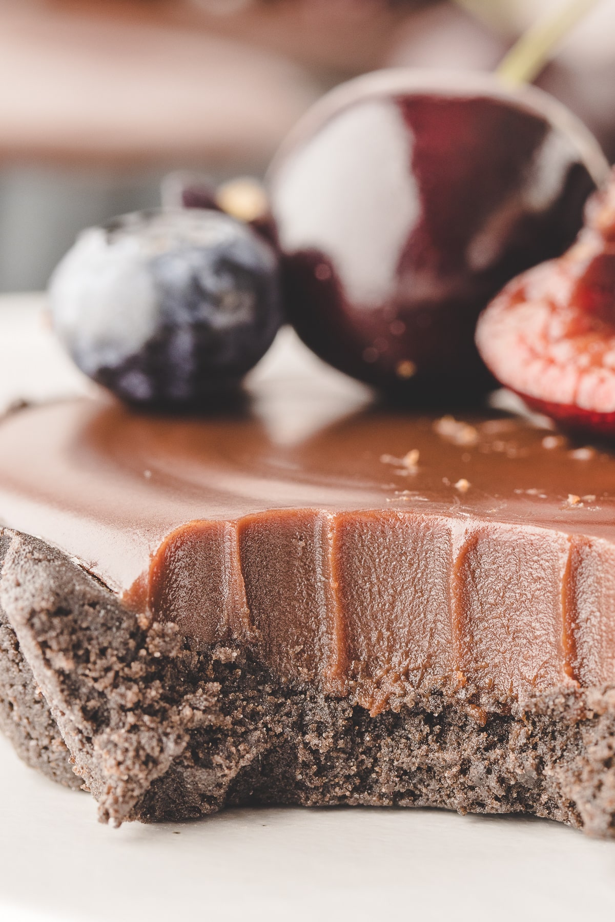 Close-up detail of a mini chocolate ganache tart with a bite removed, highlighting the creamy ganache texture and crumbly crust.