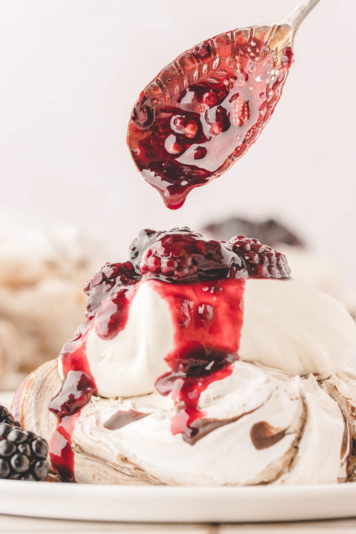 Blackberry compote spooned over whipped cream and an individual chocolate-swirled pavlova.