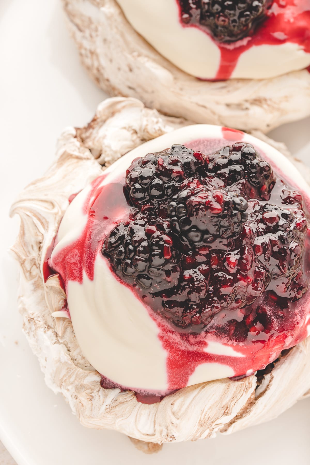 Chocolate blackberry pavlova topped with softly whipped cream and whole blackberries in blackberry compote.