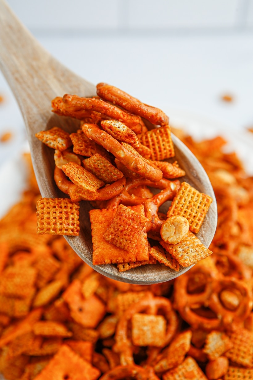 Wooden spoon scooping up some BBQ Chex snack mix.