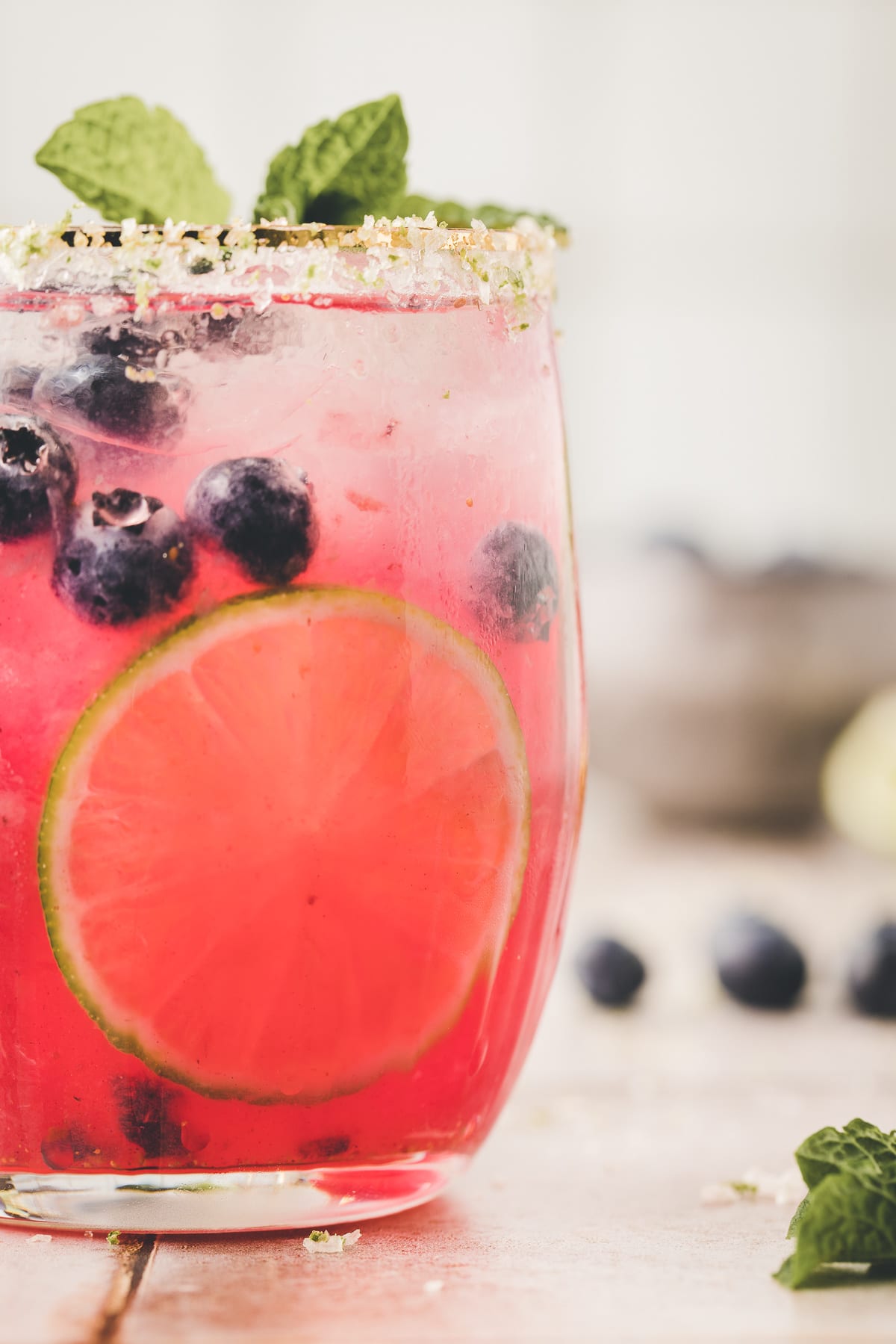 A chilled blueberry margarita with visible condensation, showing the rich color of the drink and salted rim.
