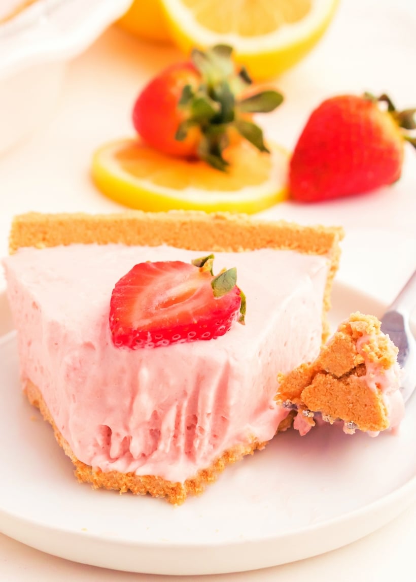 slice of no bake strawberry lemonade pie with a fork bite Close-up of strawberry lemonade pie slice with a bite on a fork