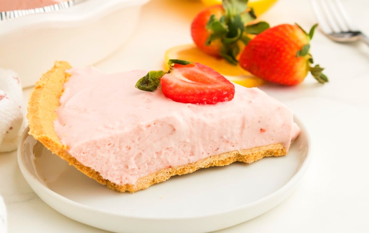 strawberry lemonade pie slice with garnish on top Side view of pie slice topped with a strawberry