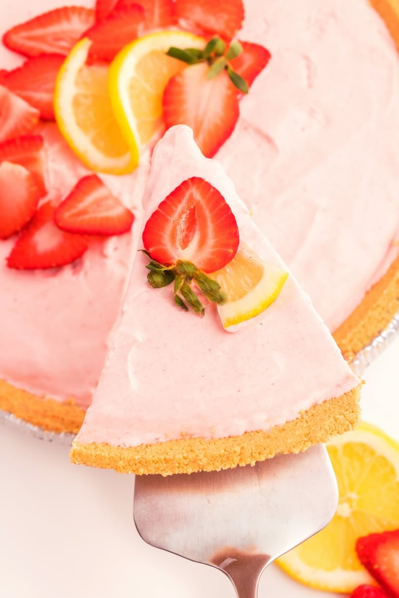 slice being lifted from full strawberry lemonade pie Top view of strawberry lemonade pie with one slice being removed