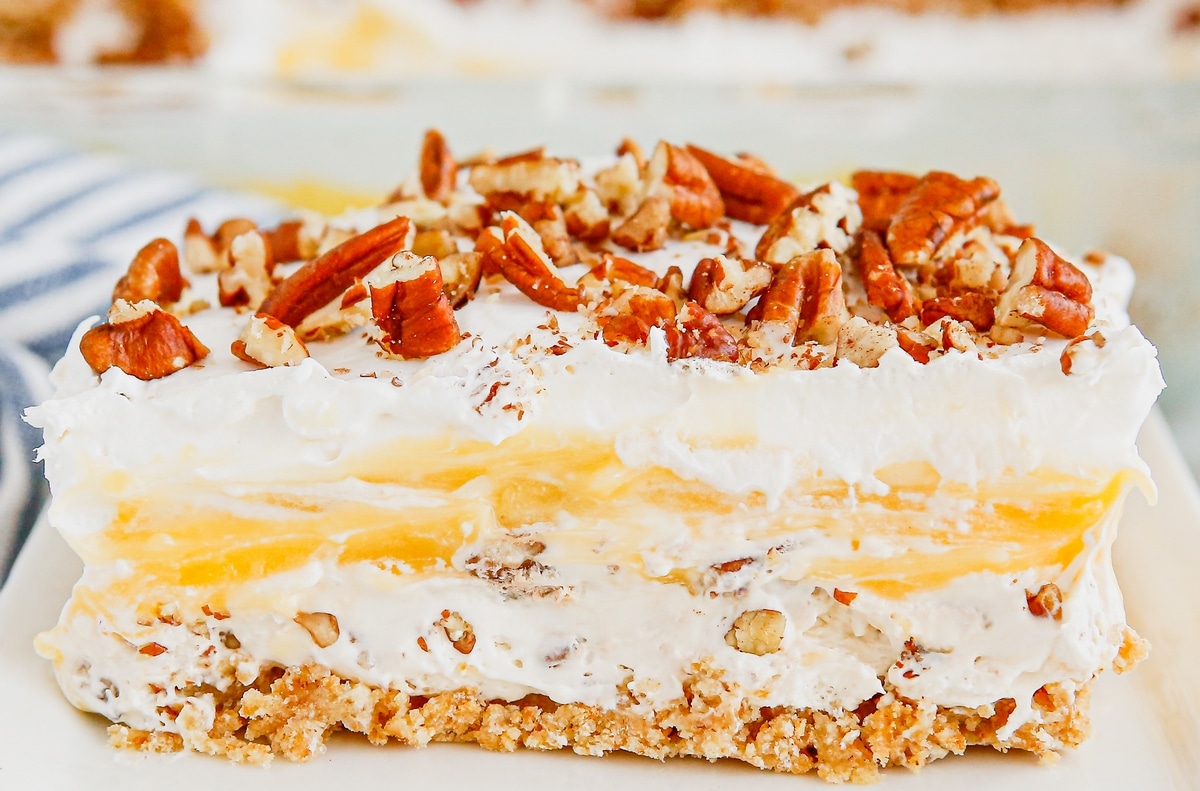 Layered Slice of Pecan Cream Pie Lush Close-up of a slice of Pecan Cream Pie Lush, showcasing distinct layers of graham cracker crust, creamy filling, and pecan topping.