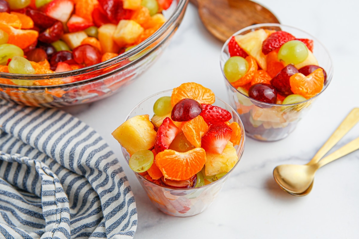 Honey Lime Fruit Salad in cups Side view of two clear cups packed with layered fruit salad, highlighting the textures and colors of the fresh fruit.