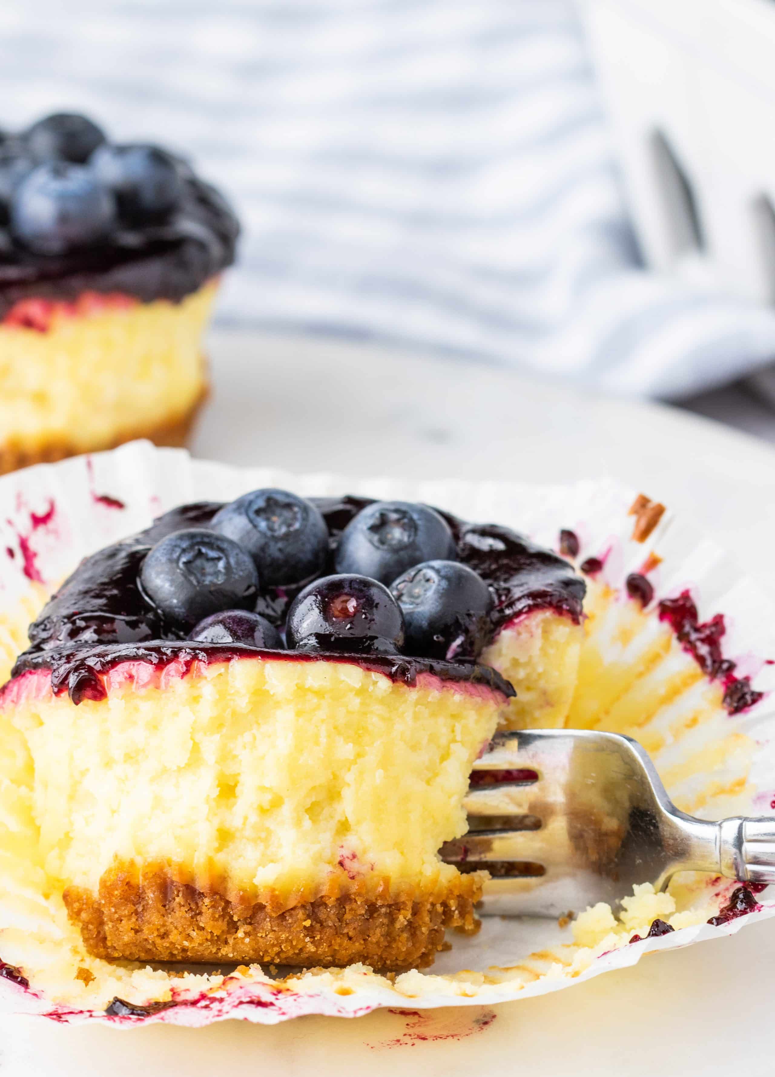  A fork slicing into a mini blueberry cheesecake