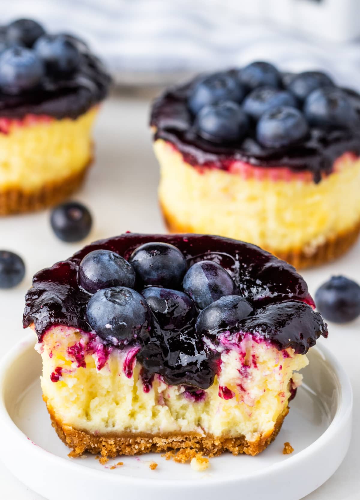 Mini blueberry-topped cheesecakes on a tray, one with a bite taken out