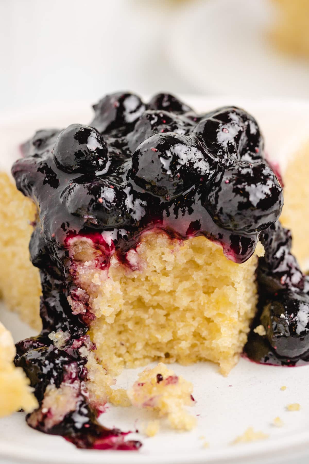 Lemon Cornmeal Cake interior piled with blueberry sauce Extreme close-up of a bite taken from the cake with sauce, highlighting the texture and glaze.
