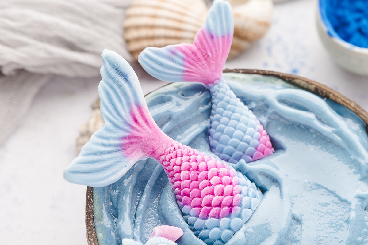 Homemade yogurt mermaid tails are surprisingly easy to make. Close-up of homemade yogurt mermaid tails decorating a blue mermaid smoothie bowl.
