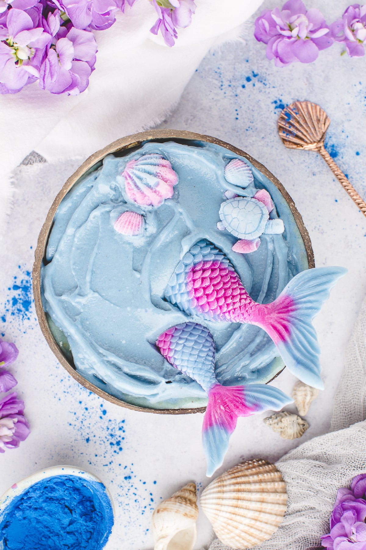 The yogurt mermaid decorations are ready before the fresh fruit is added. Blue smoothie base topped with homemade yogurt mermaid tails, seashells, and a turtle before adding fresh fruit.