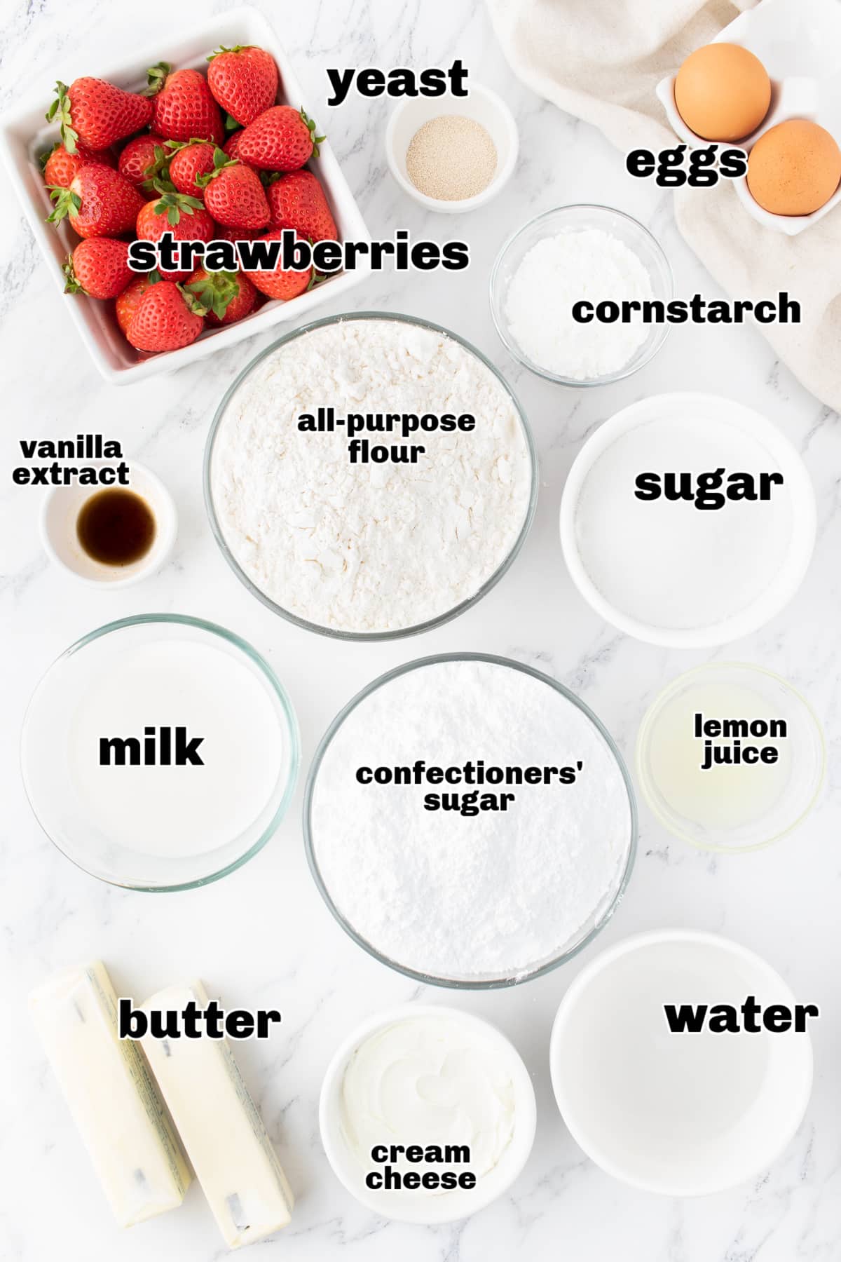 Overhead view of all the ingredients laid out for making strawberry sweet rolls, including strawberries, flour, butter, and cream cheese.