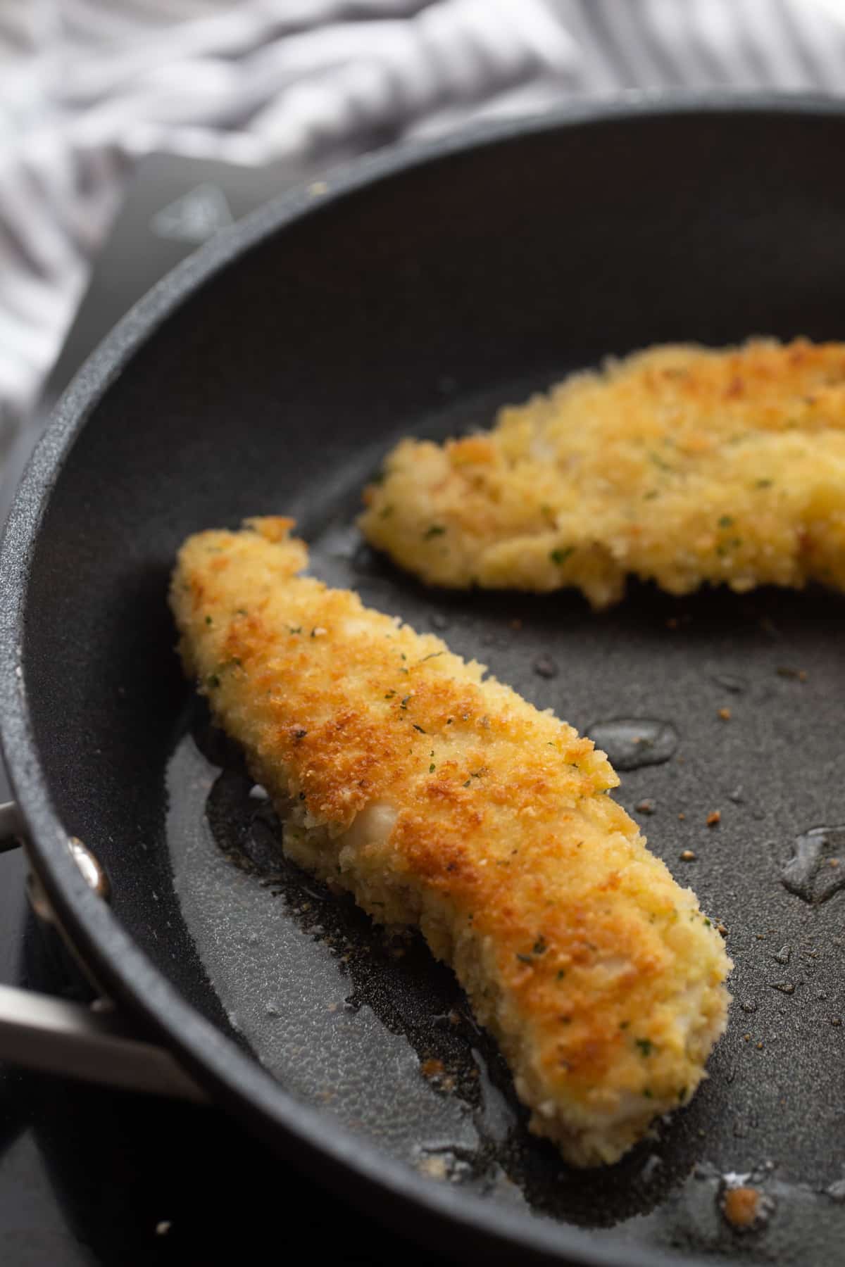 Chicken Tenderloin Piccata in a nonstick skillet Breaded chicken tenderloins sizzling in a skillet with a light golden crust forming.