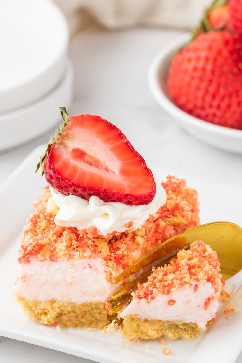 Rich and creamy cheesecake bars kissed with fresh strawberries and studded with a crumbly strawberry crunch are the official answer to what to serve to your favorite people in the coming weeks. With a quick press-in golden Oreo crust, a simple cream cheese base, and a short trip to the oven, they couldn’t be easier to make. These bars are a treat fit for a celebration. strawberry crunch cheesecake bars