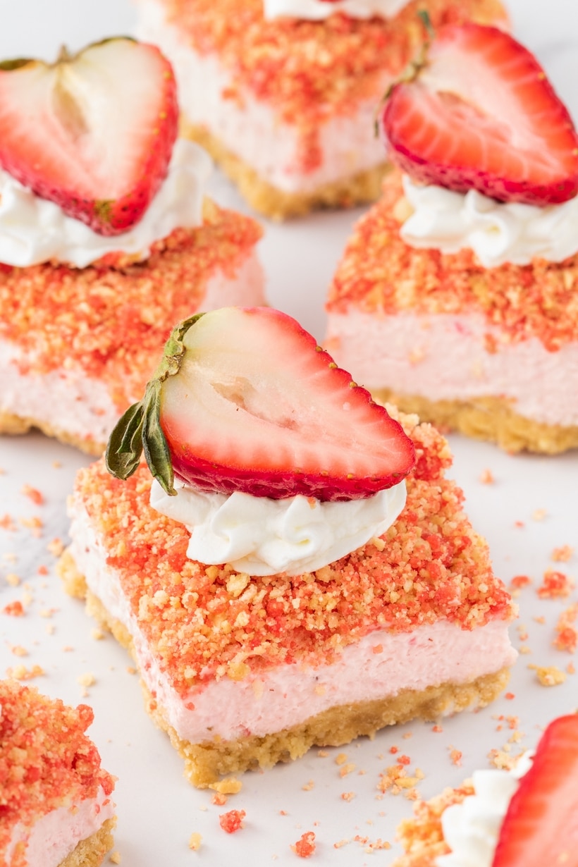Rich and creamy cheesecake bars kissed with fresh strawberries and studded with a crumbly strawberry crunch are the official answer to what to serve to your favorite people in the coming weeks. With a quick press-in golden Oreo crust, a simple cream cheese base, and a short trip to the oven, they couldn’t be easier to make. These bars are a treat fit for a celebration. strawberry cheesecake crunch