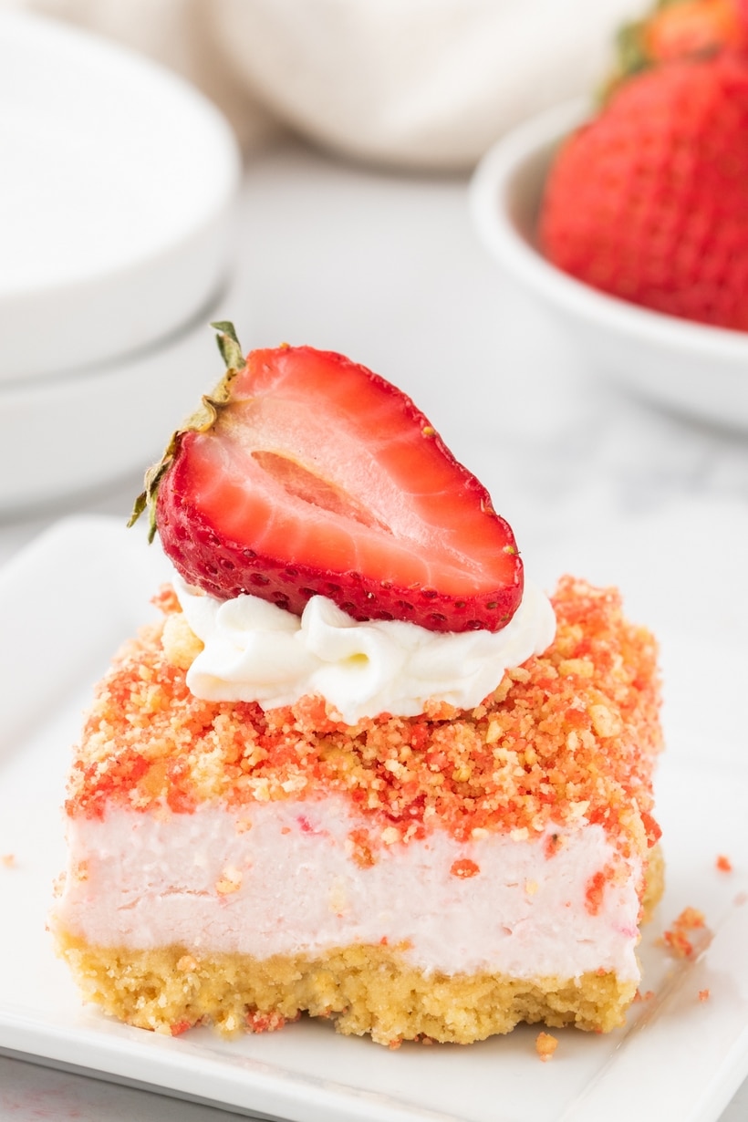 Rich and creamy cheesecake bars kissed with fresh strawberries and studded with a crumbly strawberry crunch are the official answer to what to serve to your favorite people in the coming weeks. With a quick press-in golden Oreo crust, a simple cream cheese base, and a short trip to the oven, they couldn’t be easier to make. These bars are a treat fit for a celebration. cheesecake bars