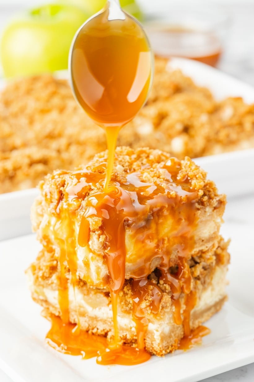 Caramel apple cheesecake bars with drizzle. Caramel apple cheesecake bars stacked and drizzled with caramel sauce.