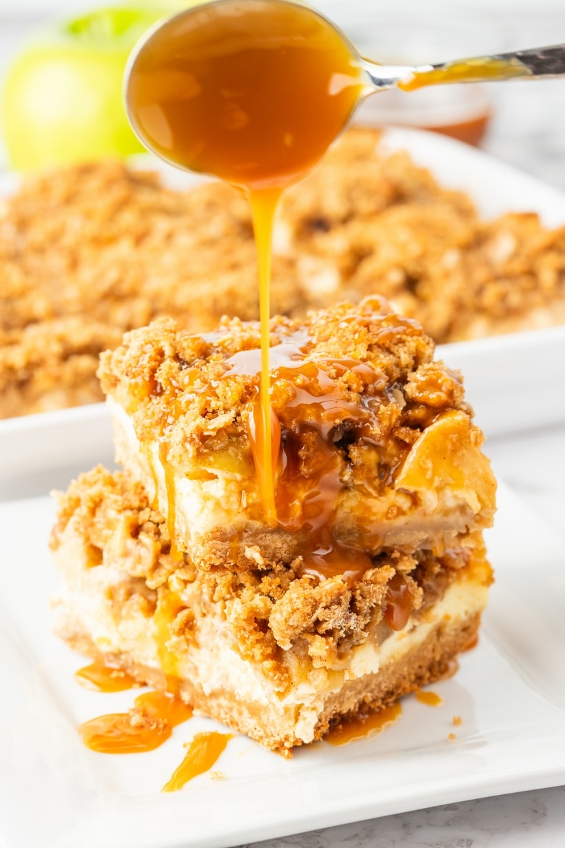 Apple streusel cheesecake bars with caramel drizzle. Close-up of apple streusel cheesecake bars with caramel poured over the top.