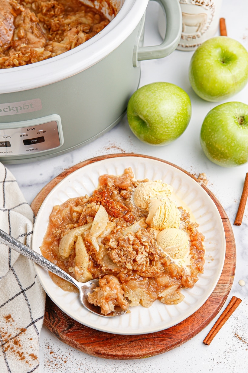 Homemade apple crisp with oats and cinnamon baked in the crockpot, served warm with ice cream.