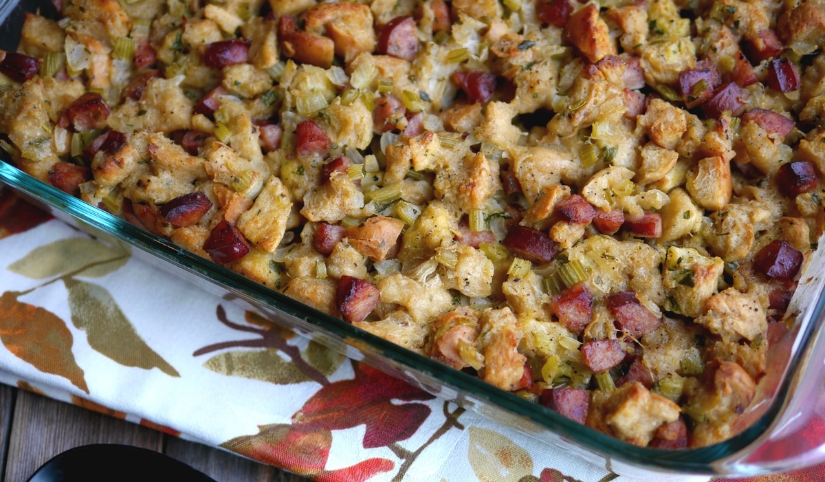 Overhead view of golden-brown challah bread and kielbasa stuffing in a baking dish.