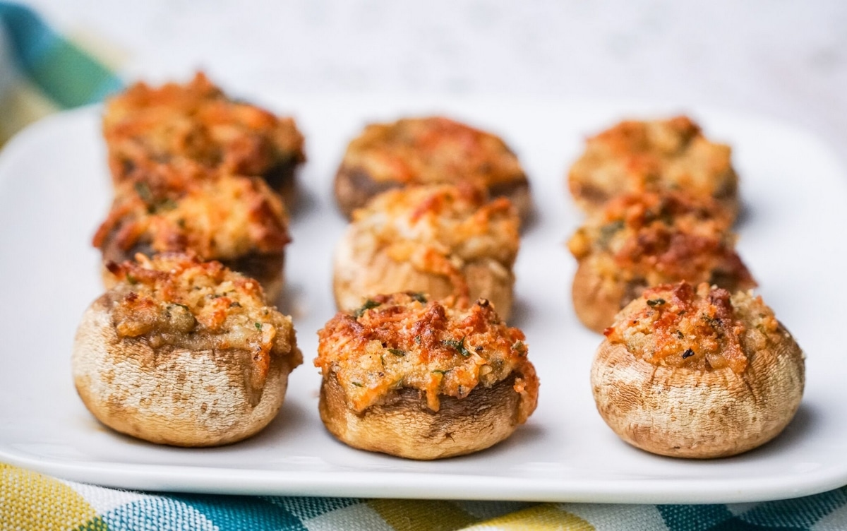 Italian stuffed mushrooms served on a white platter. Side view of Italian stuffed mushrooms on a white platter.