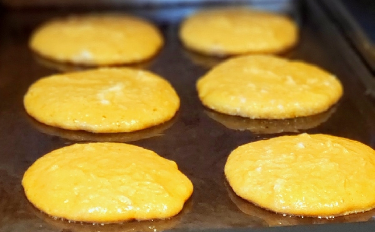 Pumpkin pancake batter cooking on a hot griddle.