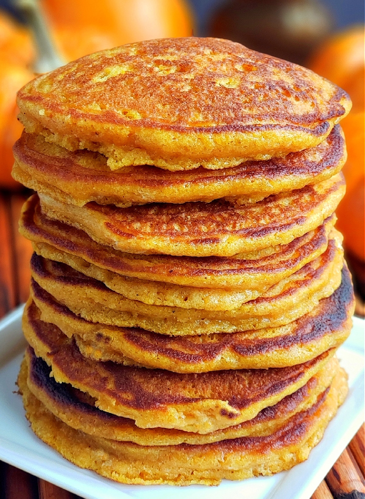 Homemade pumpkin pancakes stacked on a white plate.