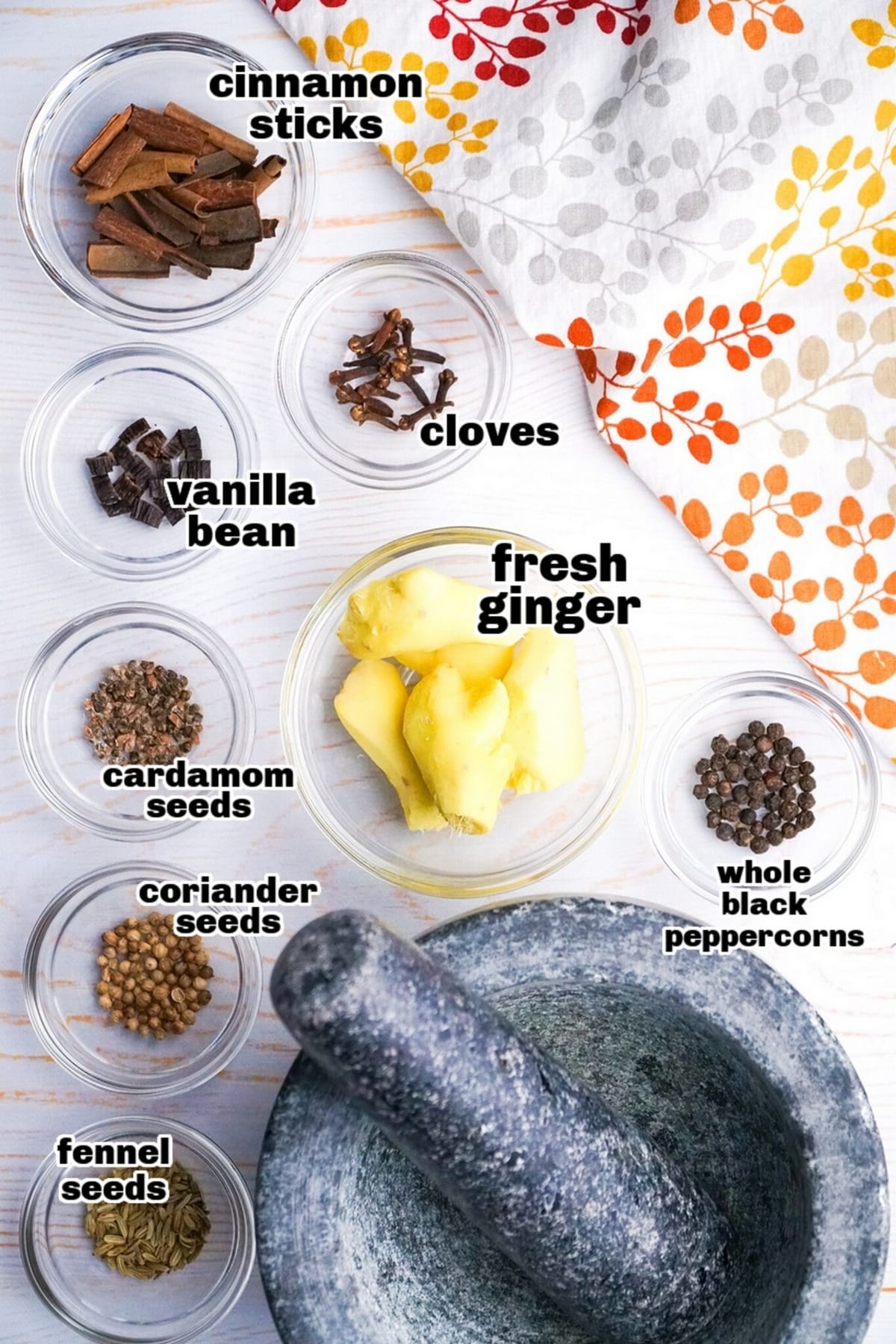 Whole spices including cloves, cinnamon sticks, cardamom, and fennel seeds arranged on a countertop.