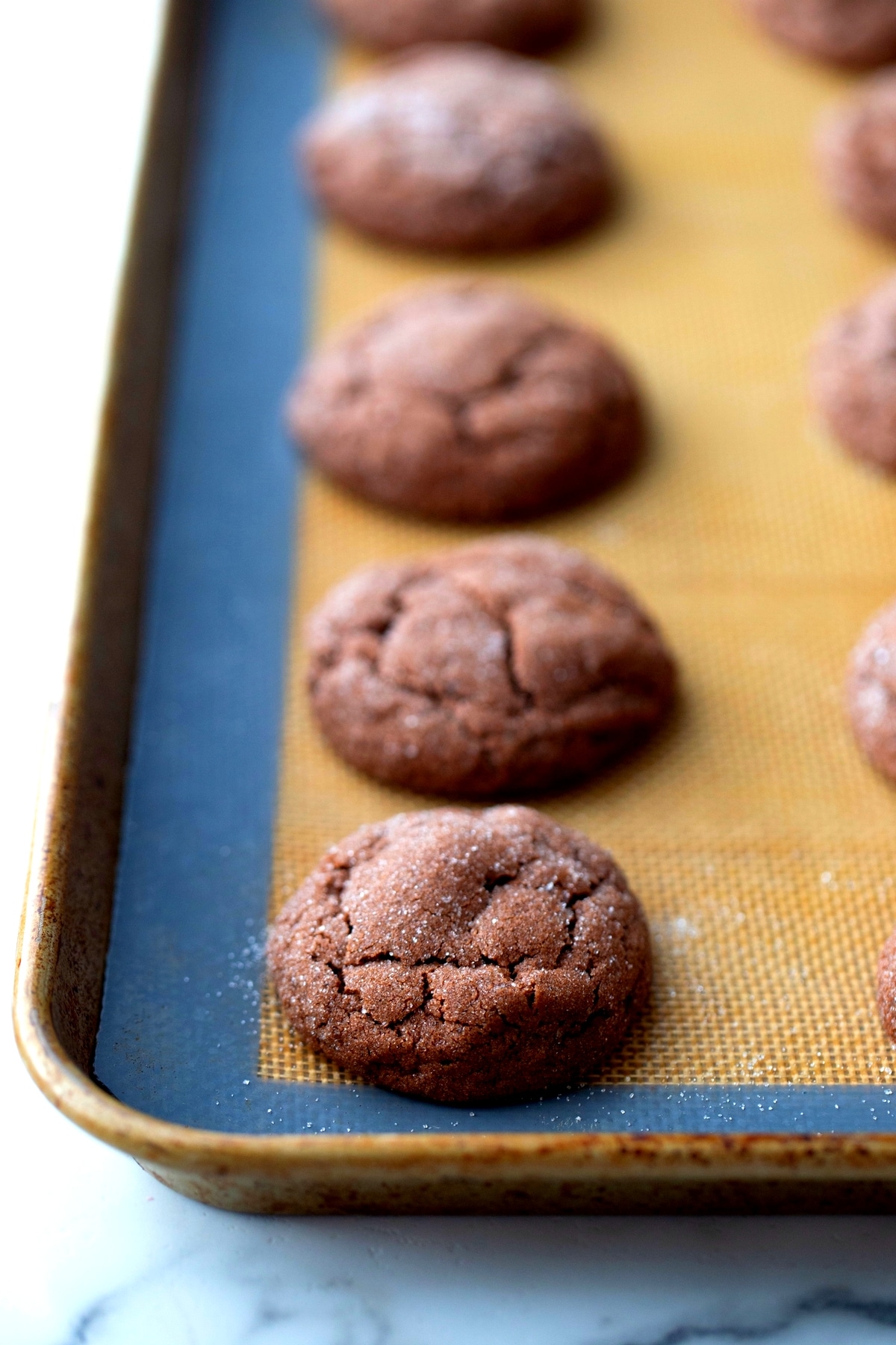 Freshly baked Dark Chocolate Peppermint Crackle Cookies cooling on a silicone mat.