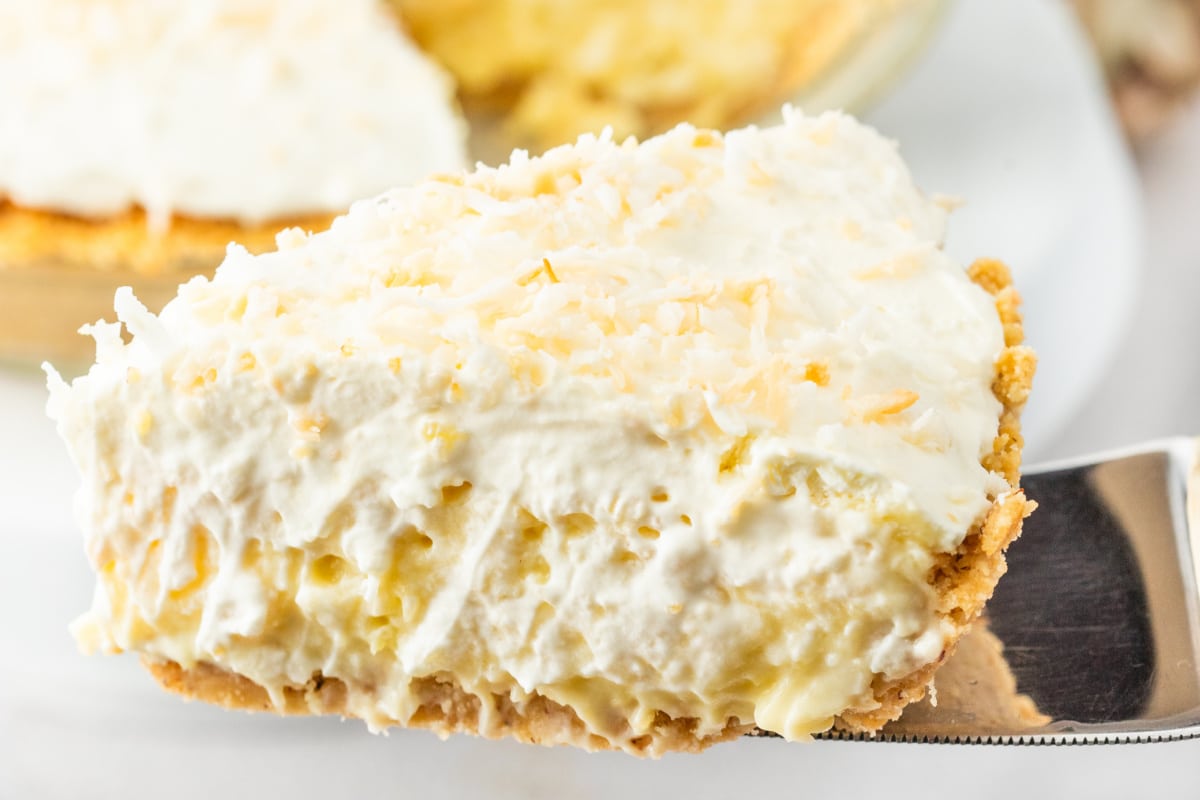 Side angle of a pie slice showing the layered cookie crust, creamy filling, and whipped topping. 
