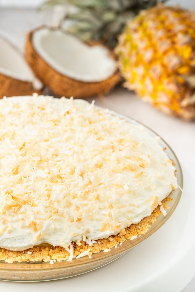 Overhead view of a full pineapple coconut cream pie topped with whipped cream and toasted coconut.