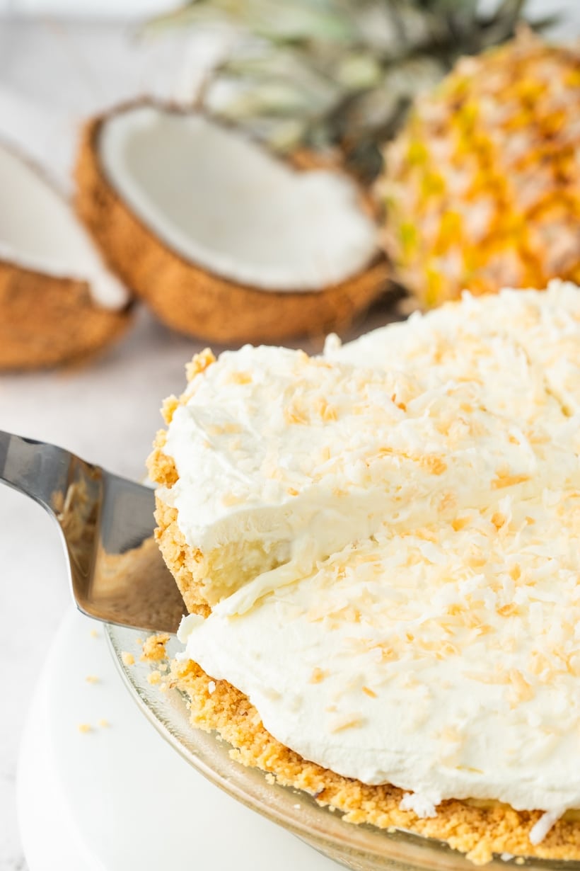 A spatula lifting a slice of pie from the dish, showing the creamy filling and crumb crust.