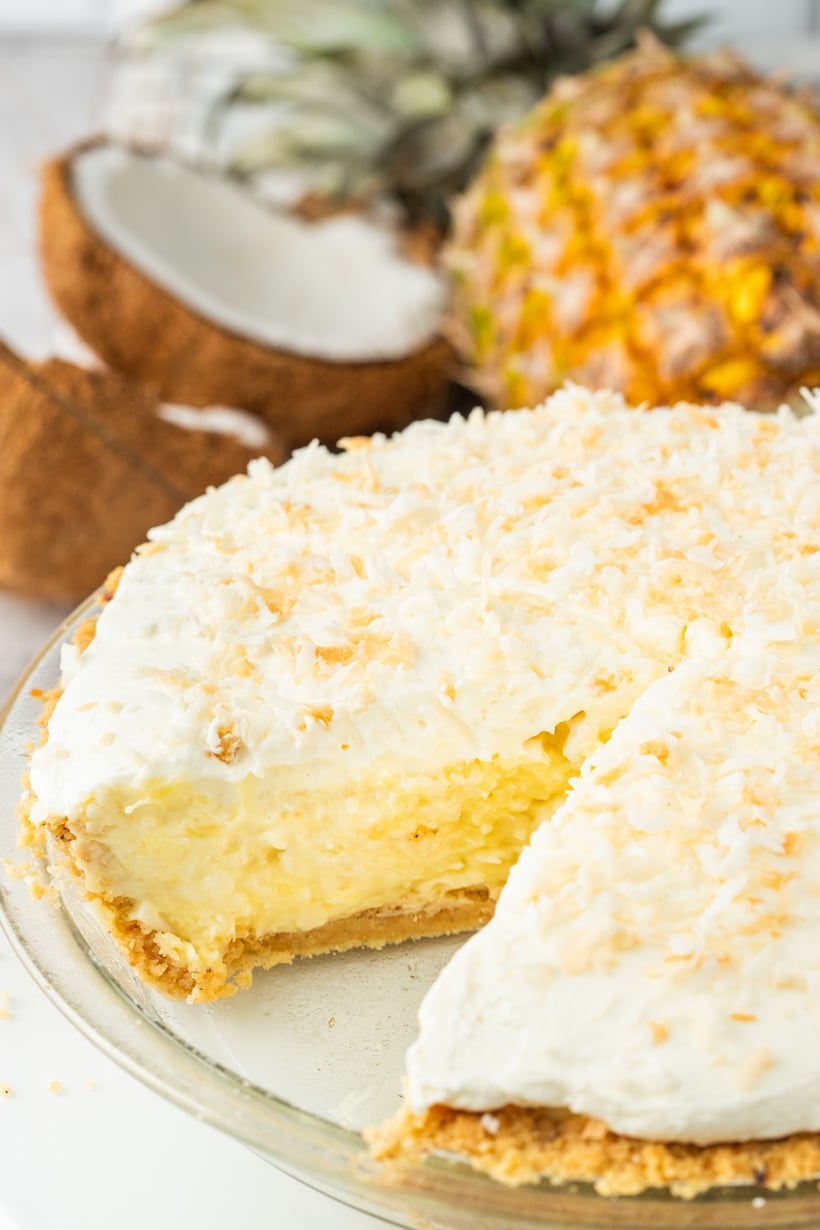 Pineapple coconut cream pie with one slice removed, revealing the inside texture.