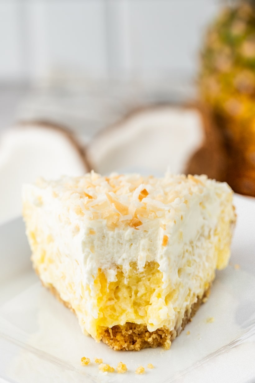 Close-up of a pie slice with a bite taken out, showing the smooth filling and toasted coconut topping.