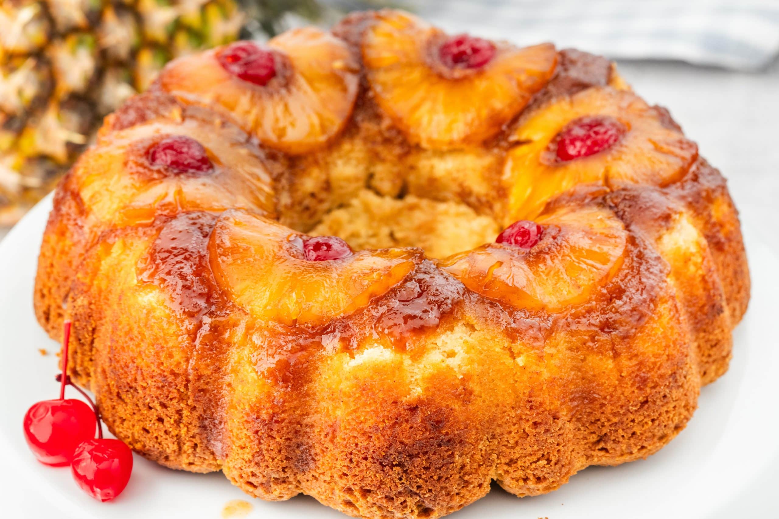 Whole Greek yogurt Pineapple Upside Down Bundt Cake with Classic Topping Full pineapple upside down Bundt cake with Greek yogurt topped with caramelized pineapple slices and maraschino cherries.