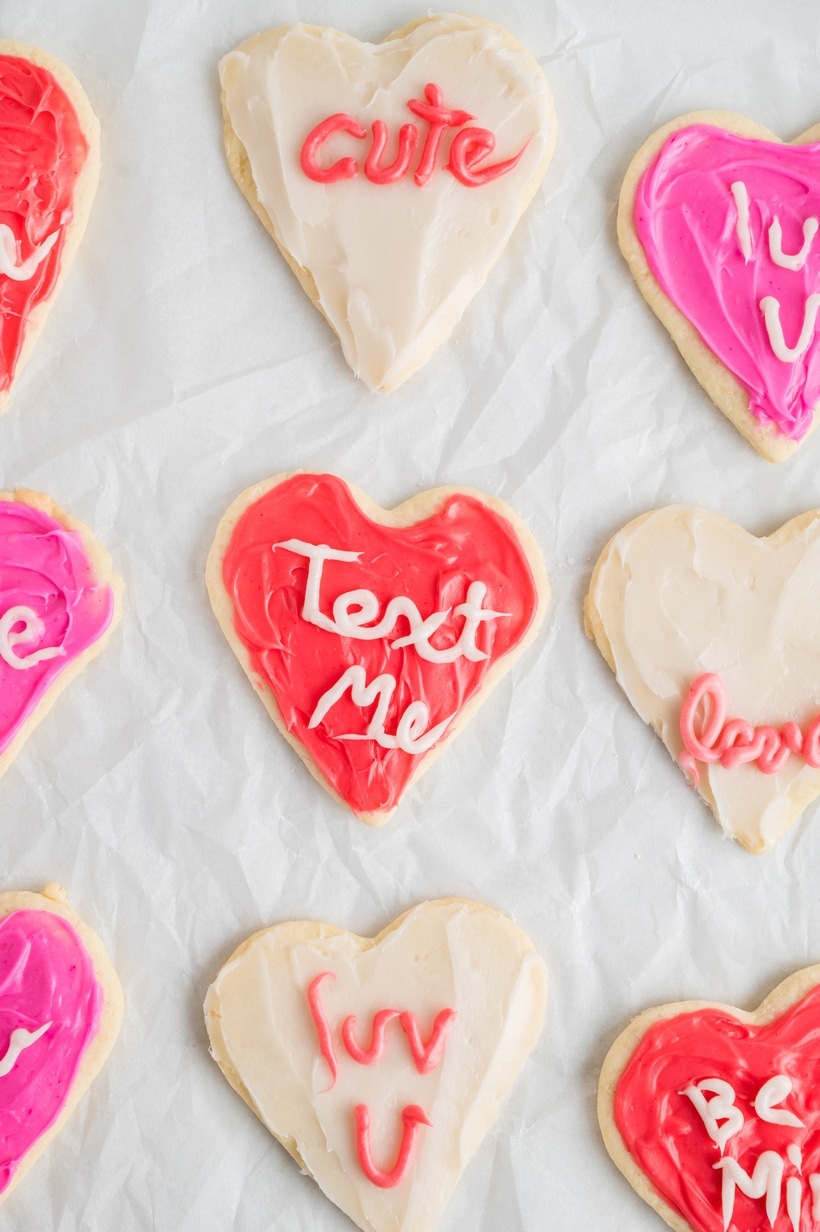 Heart-Shaped Sugar Cookies on the counter Close-up of heart-shaped sugar cookies decorated with pink, red, and white frosting, resembling conversation heart candies.