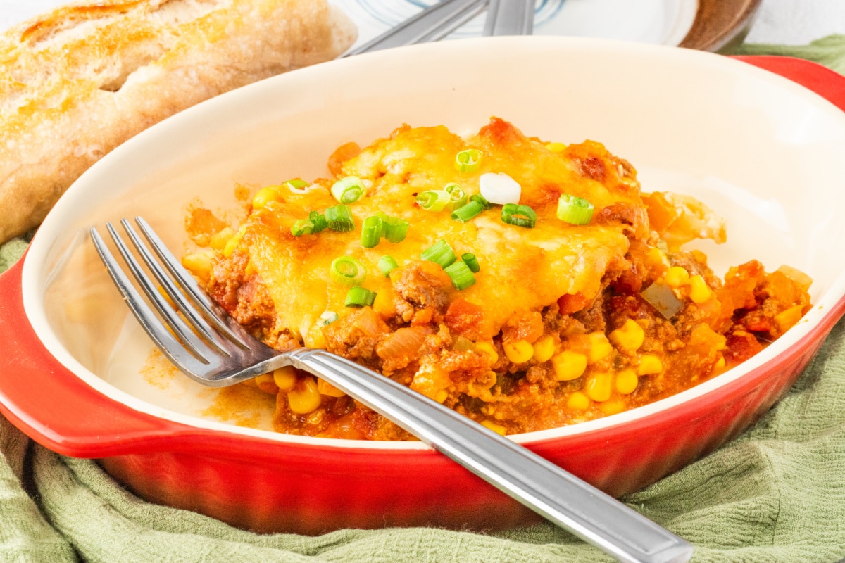 Cheesy ground beef casserole served with bread and topped with green onions
