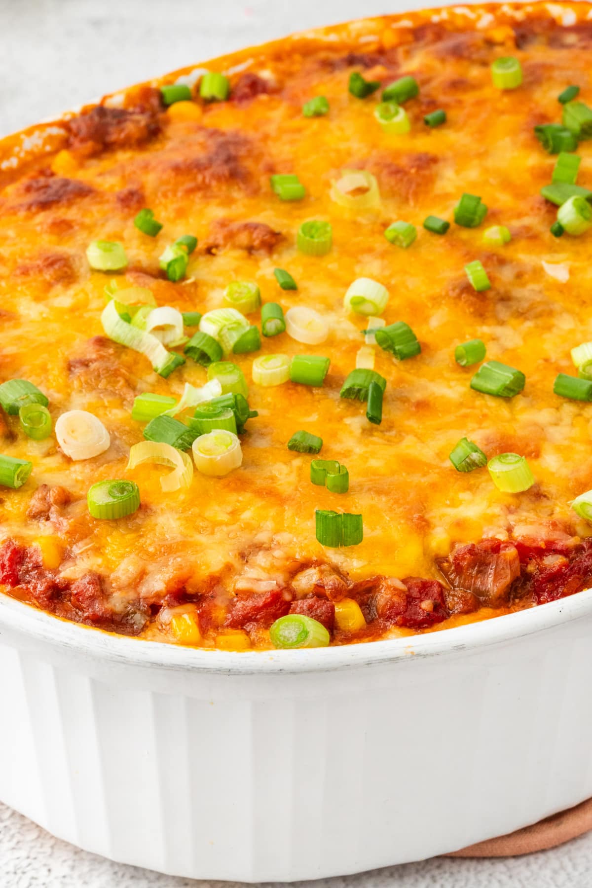 Baked ground beef casserole with melted cheddar and green onion topping