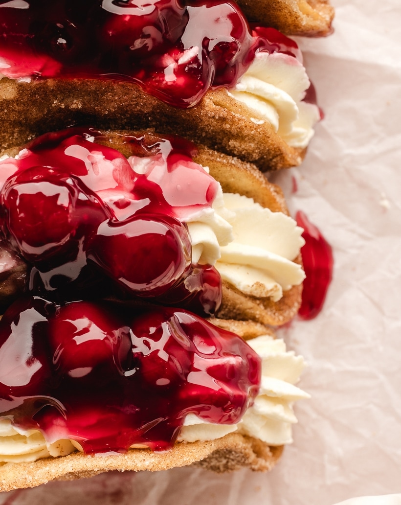 Overhead view of a cherry cheesecake taco filled with whipped cheesecake and topped with cherry pie filling.